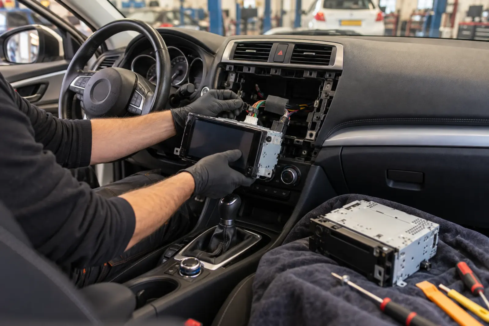 Android Auto radio inbouwen in Oss: monteur haalt de oude autoradio uit het dashboard terwijl het nieuwe toestel klaarligt